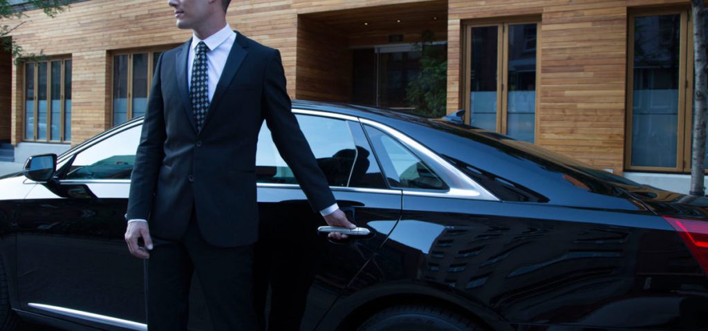 Limousine service where private chauffeur opens back door to black limousine